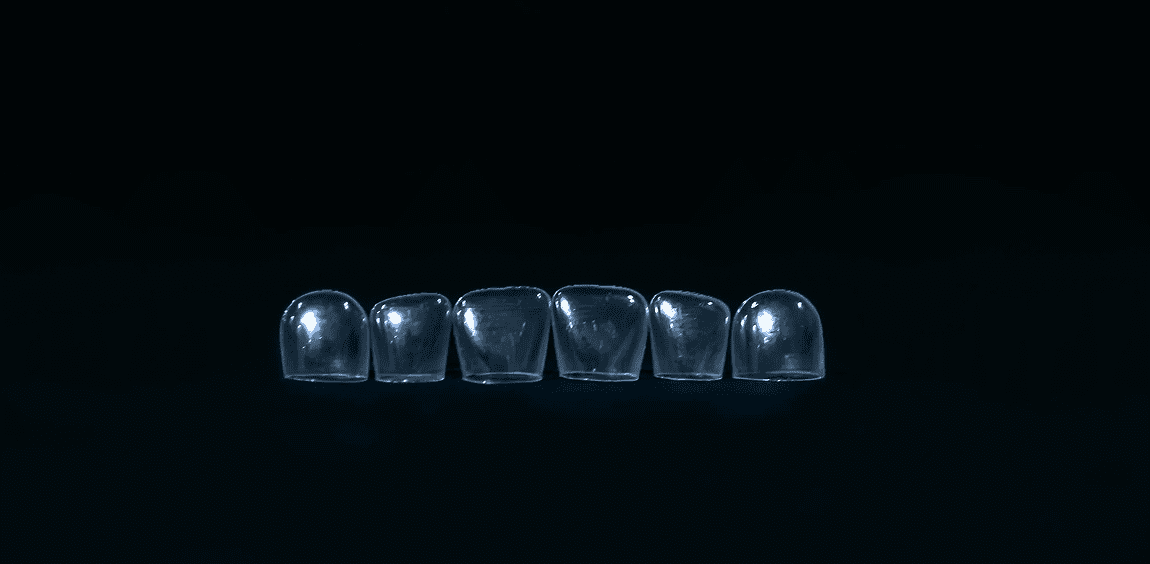 Six clear dental aligners on black background